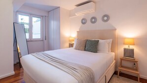 Een slaapkamer met een groot bed, bedlampen, een raam en een airconditioning.