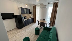 Un espai habitable compacte amb una petita cuina, zona de menjador i un sofà verd.