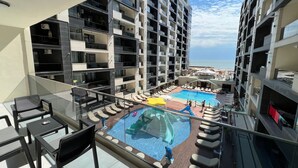 Un hotel modern amb piscina al terrat, zona de seients exteriors i vistes a l'oceà.