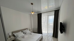 Habitació d'hotel moderna amb un llit gran, aburnissos, vista a l'exterior i una làmpada al sostre.