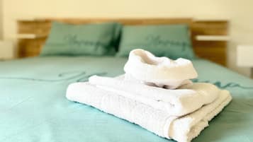 Un letto ben rifatto con una coperta verde e due cuscini con scritte sopra.
