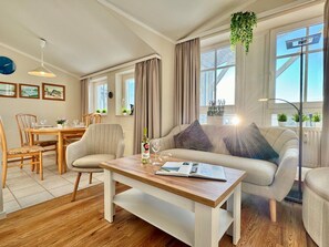 A modern living room with a wooden dining table, a sofa, and a coffee table. - Komfortable Ferienwohnung in Sellin mit Balkon (Sellin)