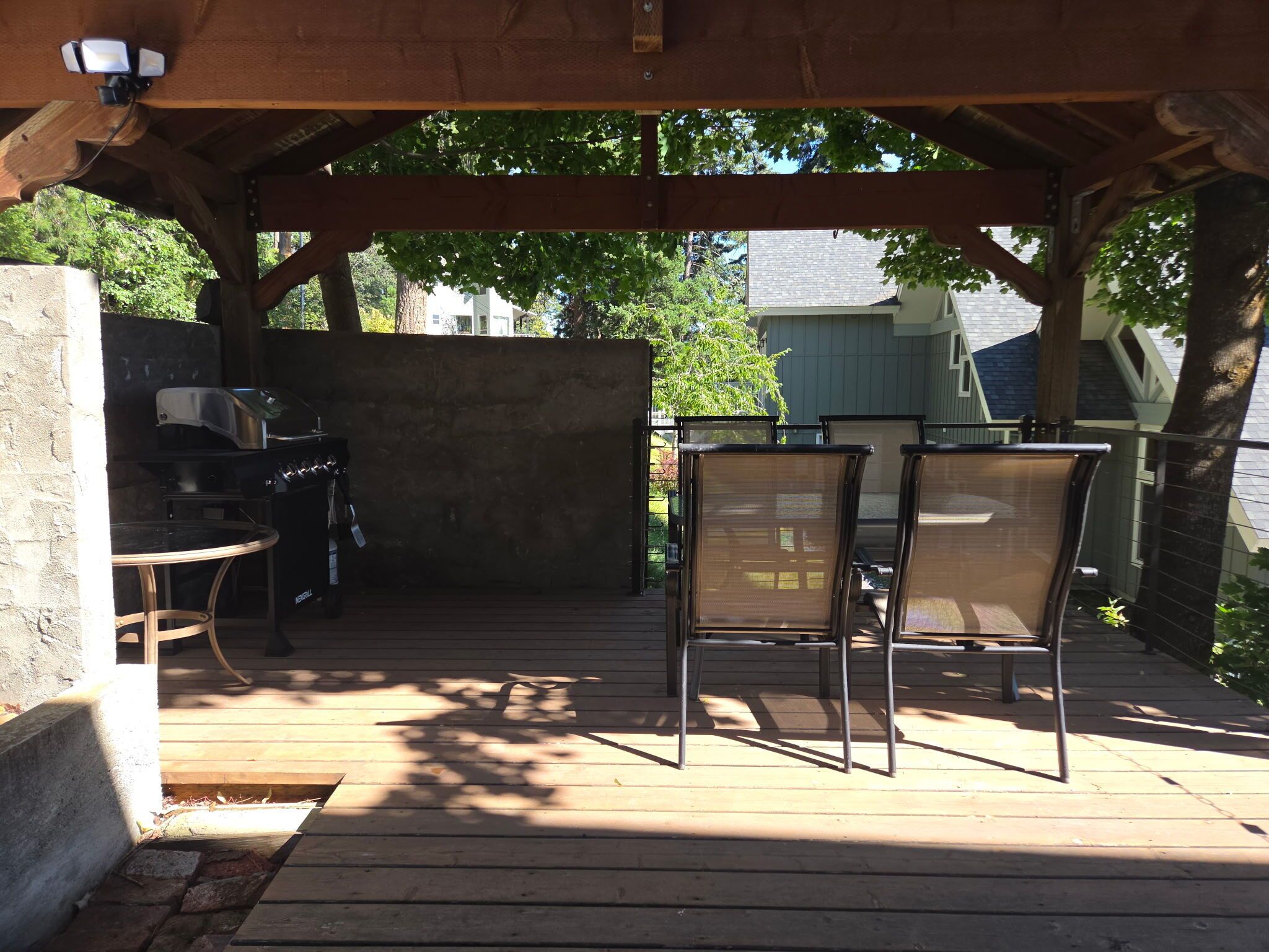 Un patio al aire libre con una parrilla, dos sillas y una mesa.