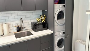 Eine moderne Küche mit Einbauwaschmaschine, Mikrowelle und Spüle.