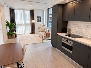 Una cocina moderna con gabinetes oscuros, encimera negra y horno empotrado.