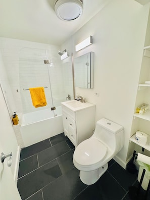 Une salle de bain moderne équipée d’une baignoire, de toilettes et d’une douche à parois en verre.