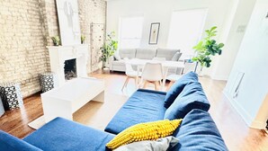 A modern living room with a blue sofa, a fireplace, and a dining area. - Modern& Spacious 2BR in Prime Location with 1 Parking Spot (Chicago)