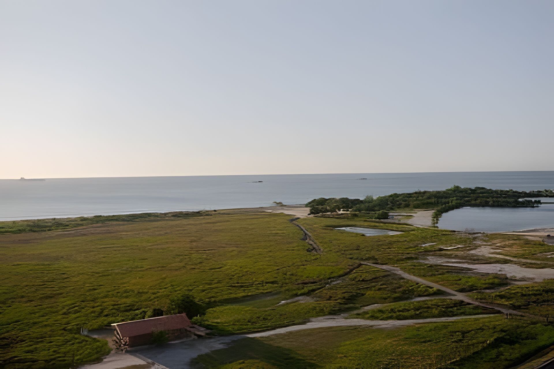 A coastal landscape with a small building, a path, and a body of water.