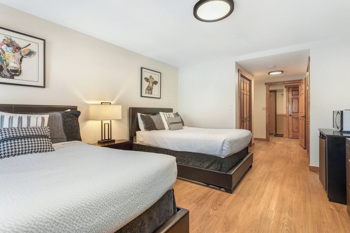 Een hotelkamer met twee bedden, een nachtkastje, een lamp en een ingelijst schilderij aan de muur.