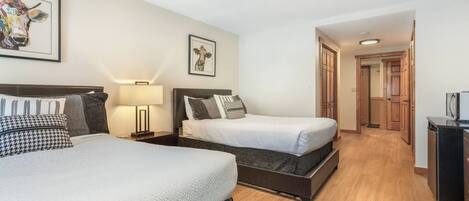 Een hotelkamer met twee bedden, een nachtkastje, een lamp en een ingelijst schilderij aan de muur.
