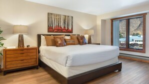 A bedroom with a large bed, two bedside tables, a nightstand, a painting, and a window with a view. - Ski Beaver Creek | Walk to Gondola (Avon)