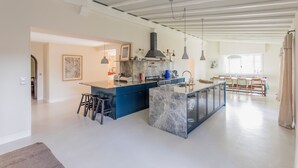 A modern kitchen with a marble island, pendant lights, and a view into the dining area. - La Grange House, a charming property with a pool - Sleeps 10 - 5 Cantons (Anglet)
