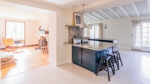 A spacious kitchen with a marble countertop, dark cabinetry, and a central island with stools. - La Grange House, a charming property with a pool - Sleeps 10 - 5 Cantons (Anglet)