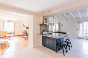 A spacious kitchen with a marble countertop, dark cabinetry, and a central island with stools.