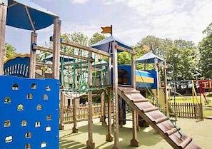 A playground with climbing structures, slides, and a blue playhouse. - Atlantic 25 | Contemporary 4BR Holiday Pad Newquay (Newquay)