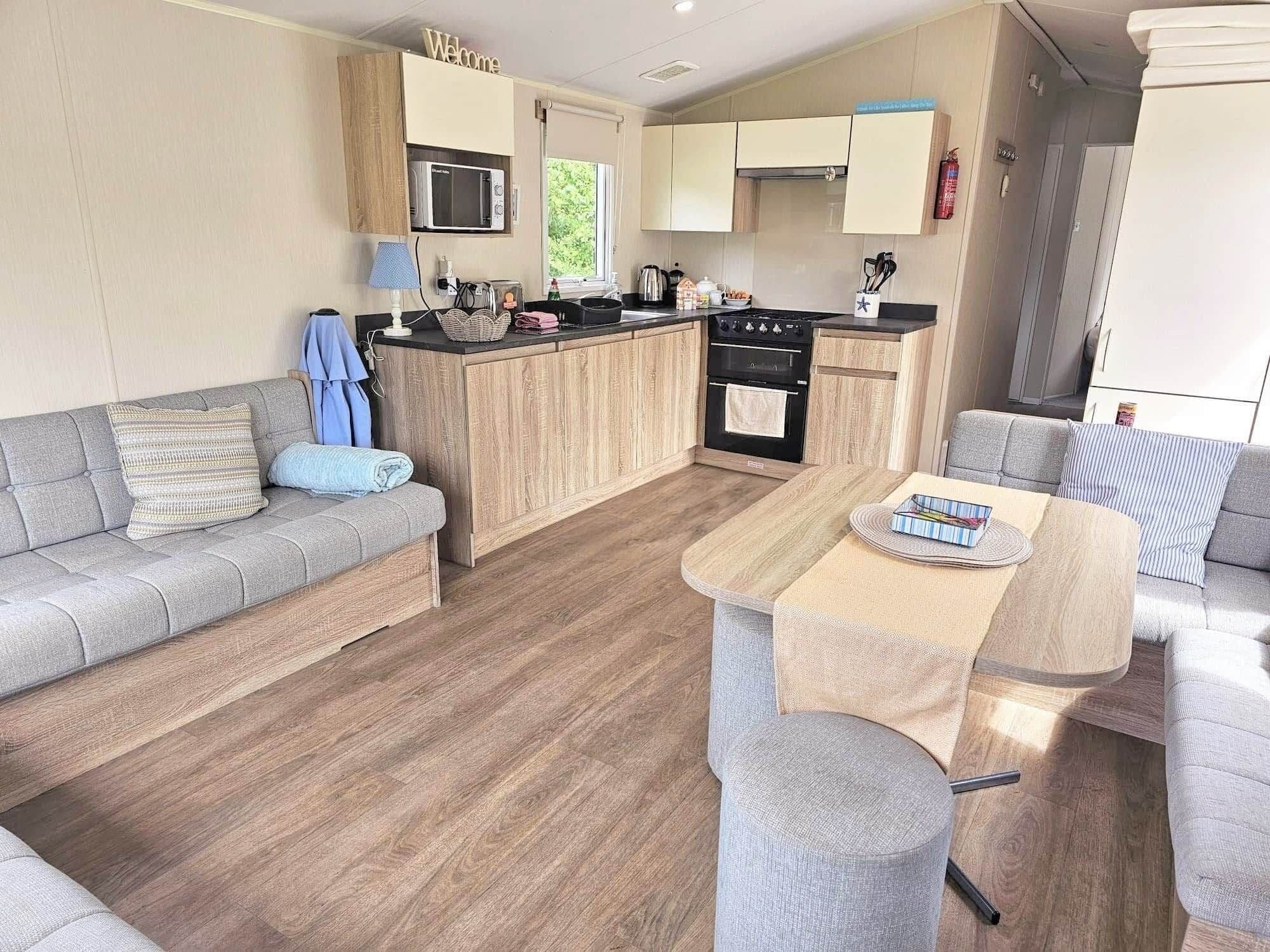 A compact living space with a kitchenette, a sofa, a dining table, and a small kitchen area.
