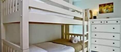 A bunk bed with a white dresser and a painting on the wall.
