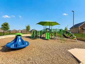 A playground with a blue spinning top, green slides, and a covered play area. - Peaceful Escape | Backyard | Community Pool & Park (Midlothian)