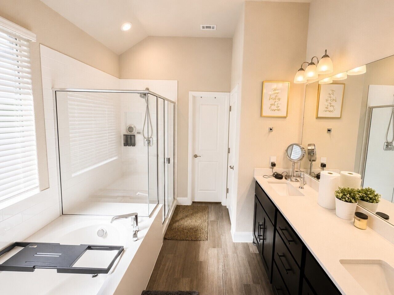 A modern bathroom with a glass-enclosed shower, a large bathtub, and a vanity with a mirror and sink.