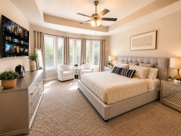 A bedroom with a bed, a ceiling fan, a TV, and a window with curtains.
