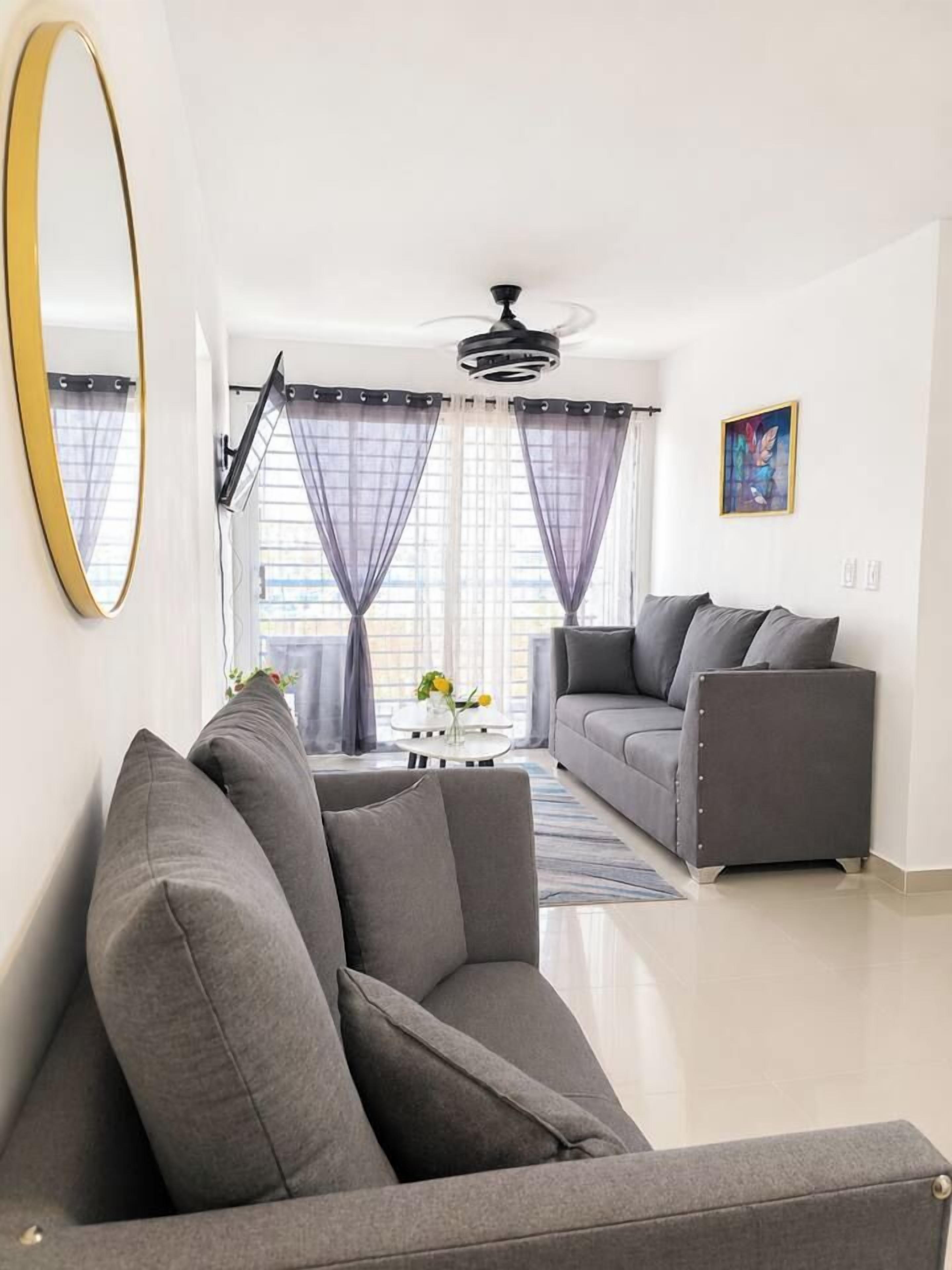 Una sala de estar moderna con un sofá gris, una mesa de centro y un cuadro en la pared.