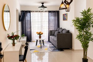 Een moderne woonkamer met een bank, een eettafel met stoelen, een vaas met bloemen en een grote kamerplant.