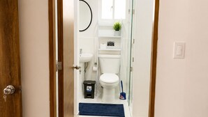 Un baño moderno con inodoro, lavamanos y un pequeño taburete.