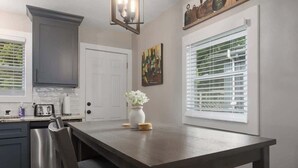 Een keuken met een donker houten tafel, een witte deur en een raam met zonwering.