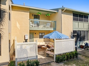 A residential building with a balcony, outdoor seating area, and a fenced patio. - Coastal Townhome in Gated Resort w Patio & Pool (Panama City Beach)