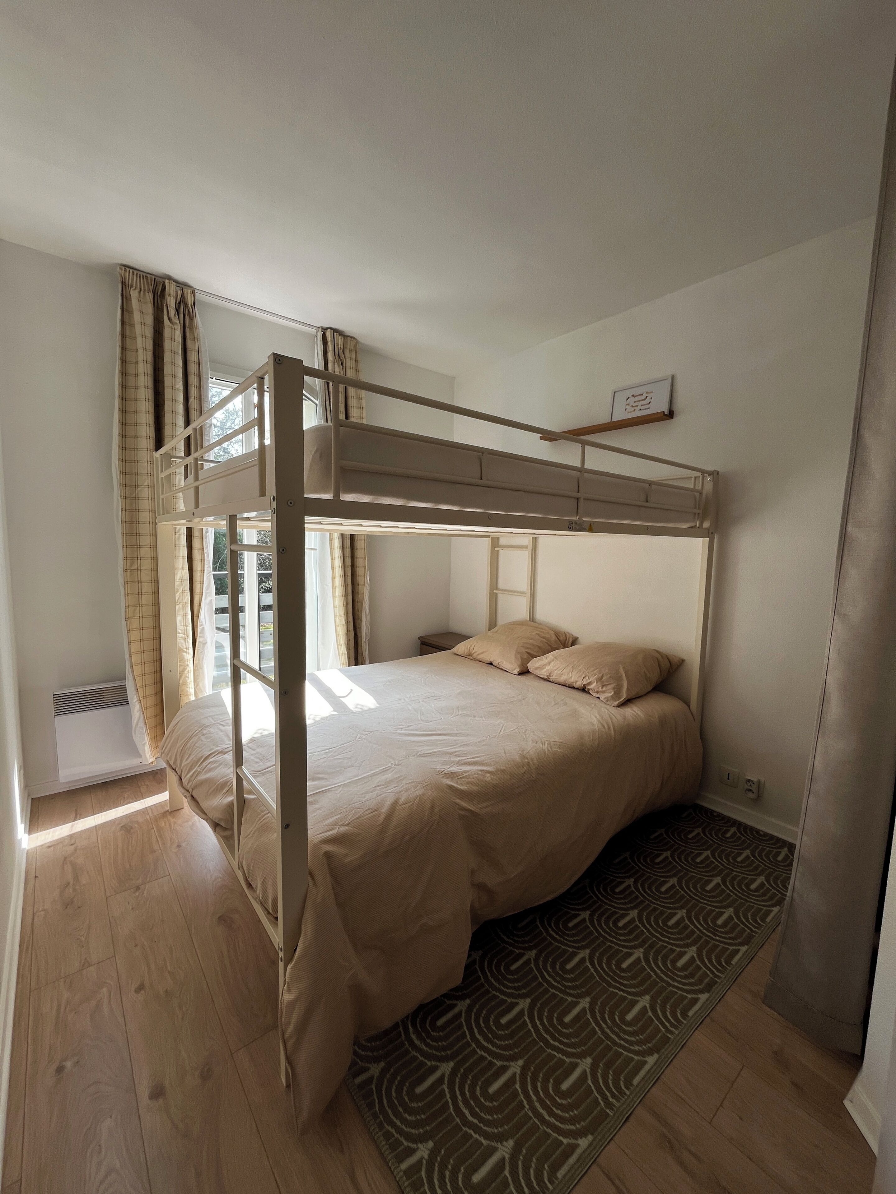 Una cama individual con ventana, una mesita de noche y una alfombra estampada.