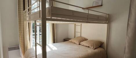 Una cama individual con ventana, una mesita de noche y una alfombra estampada.