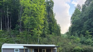 Eine Hütte mit Terrasse, Sitzgelegenheiten im Freien und einer Feuerstelle.