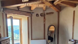 Een slaapkamer met een houten plafond, een bed met witte lakens, een dressoir en een spiegel.