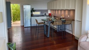 Une cuisine moderne avec des meubles blancs, un coin repas comprenant une table et des chaises, et un ventilateur de plafond.