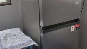 Uma geladeira de aço inoxidável com compartimento para congelador, um dispensador de água e uma pequena mesa com toalha xadrez.