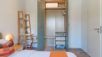 Une chambre à coucher comprenant un lit, un bureau et une armoire ouverte avec des étagères et des tiroirs.