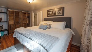 Een slaapkamer met een groot bed, een houten garderobe en een plafondlamp.
