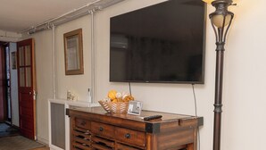 Een kamer met een houten kar, een staande lamp, een televisie en een deur.