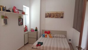 A bedroom with a bed, a dresser, a mirror, and a wall with a picture.