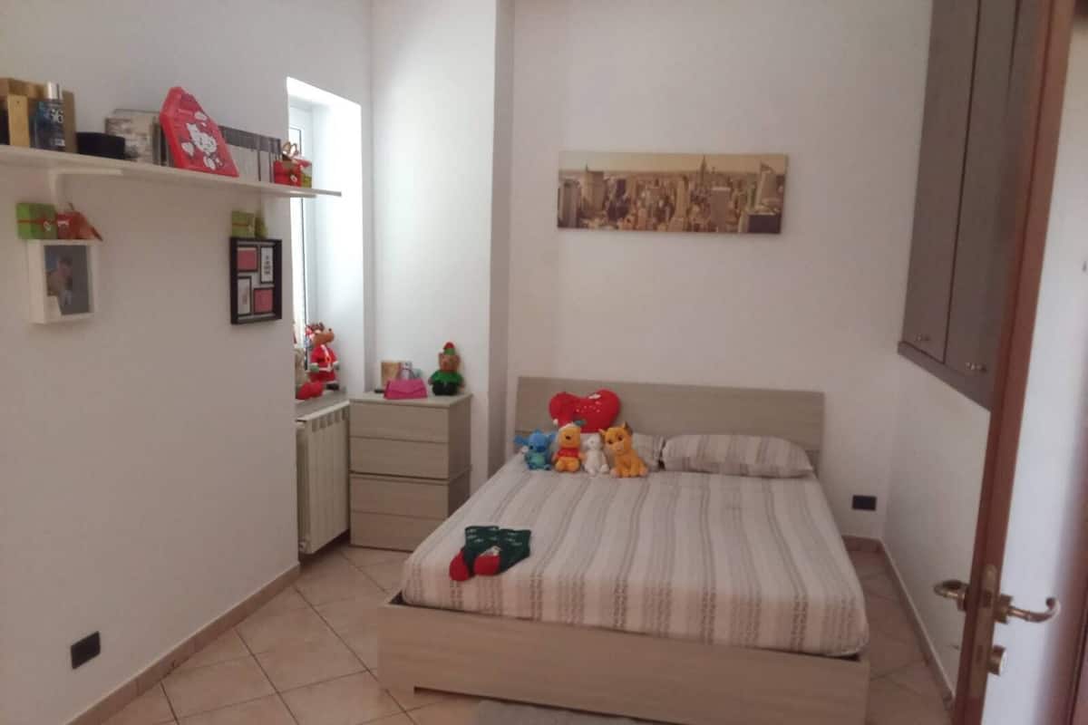 Una camera da letto con un letto, una cassettiera, uno specchio e una parete con un quadro.