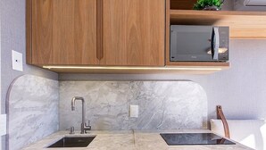 Eine moderne Küche mit Holzschränken, einer eingebauten Mikrowelle und einer Marmorarbeitsplatte.
