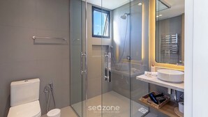 Ein modernes Badezimmer mit einer gläsernen Duschkabine, einer Toilette und einem Waschtisch mit Waschbecken und Spiegel.