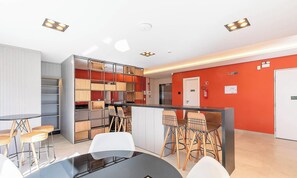 Une cuisine moderne avec un coin bar, des meubles blancs et un mur d’accent rouge.