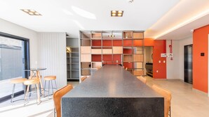 A modern kitchen with a central island, built-in shelving, and a dining area with bar stools. - Studio W/city View in Urubici Ust0506 (Urubici)