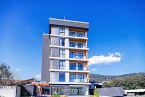 A multi-story hotel with a modern design, featuring balconies and large windows. - Comfort W/city View in Urubici Ust0506 (Urubici)