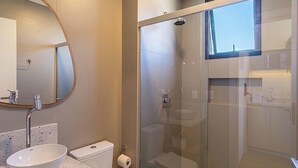 Une salle de bain moderne avec une douche à parois de verre, un miroir rond et des toilettes.