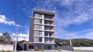 Un hotel de varios pisos con diseño moderno, que cuenta con balcones en cada planta y una vista despejada del paisaje circundante.
