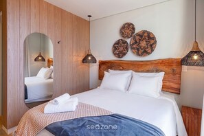 A hotel room with a wooden headboard, a large bed with white linens, a mirror, and decorative wall art. - Sophisticated Studio W/city View Urubici Ust0203 (Urubici)