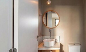 A bathroom with a round mirror, a white sink, and a toilet. - Studio w/ Balcony & Garage in Urubici Ust0101 (Urubici)