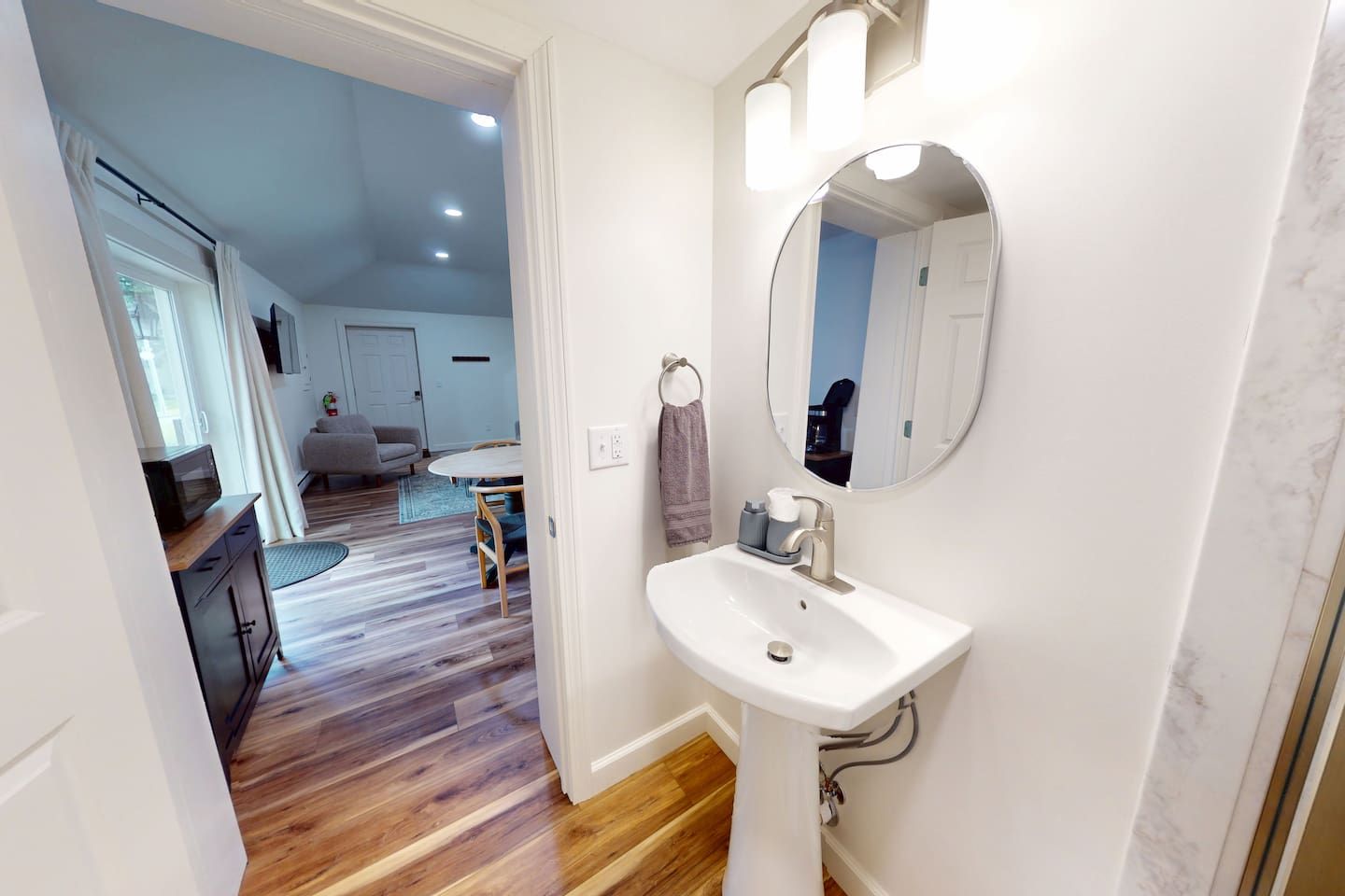 A bathroom with a white sink, a mirror, and a towel rack.